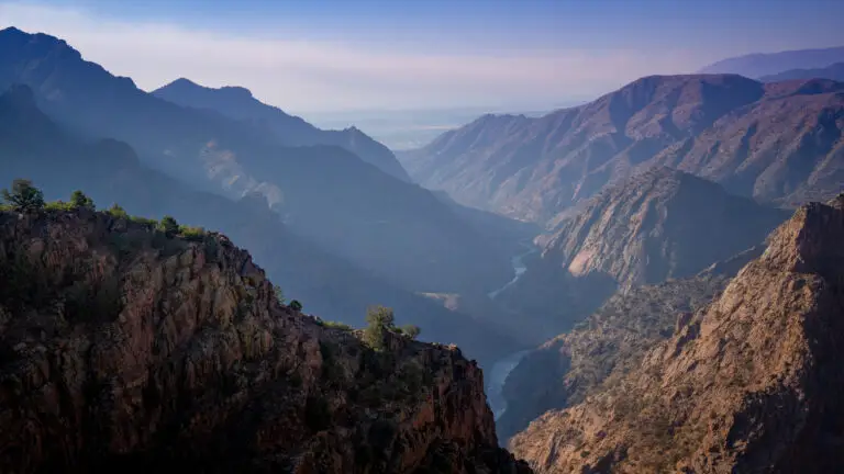 Colorado Photography Locations Colorado Photography Locations Panoramic view of a deep canyon with steep rocky walls and a winding river through the valley beneath a hazy blue sky