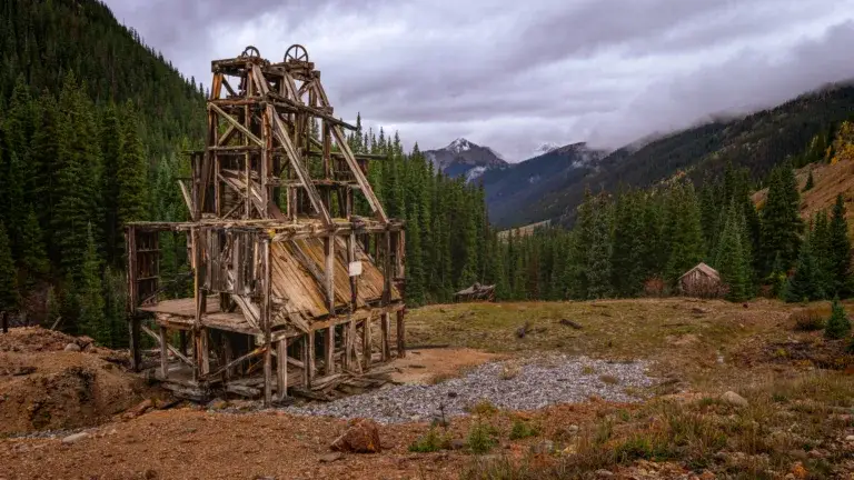 Colorado Photography Locations Colorado Photography Locations Rustic wooden mining structure in a rocky clearing with evergreen forest and misty mountains in the background
